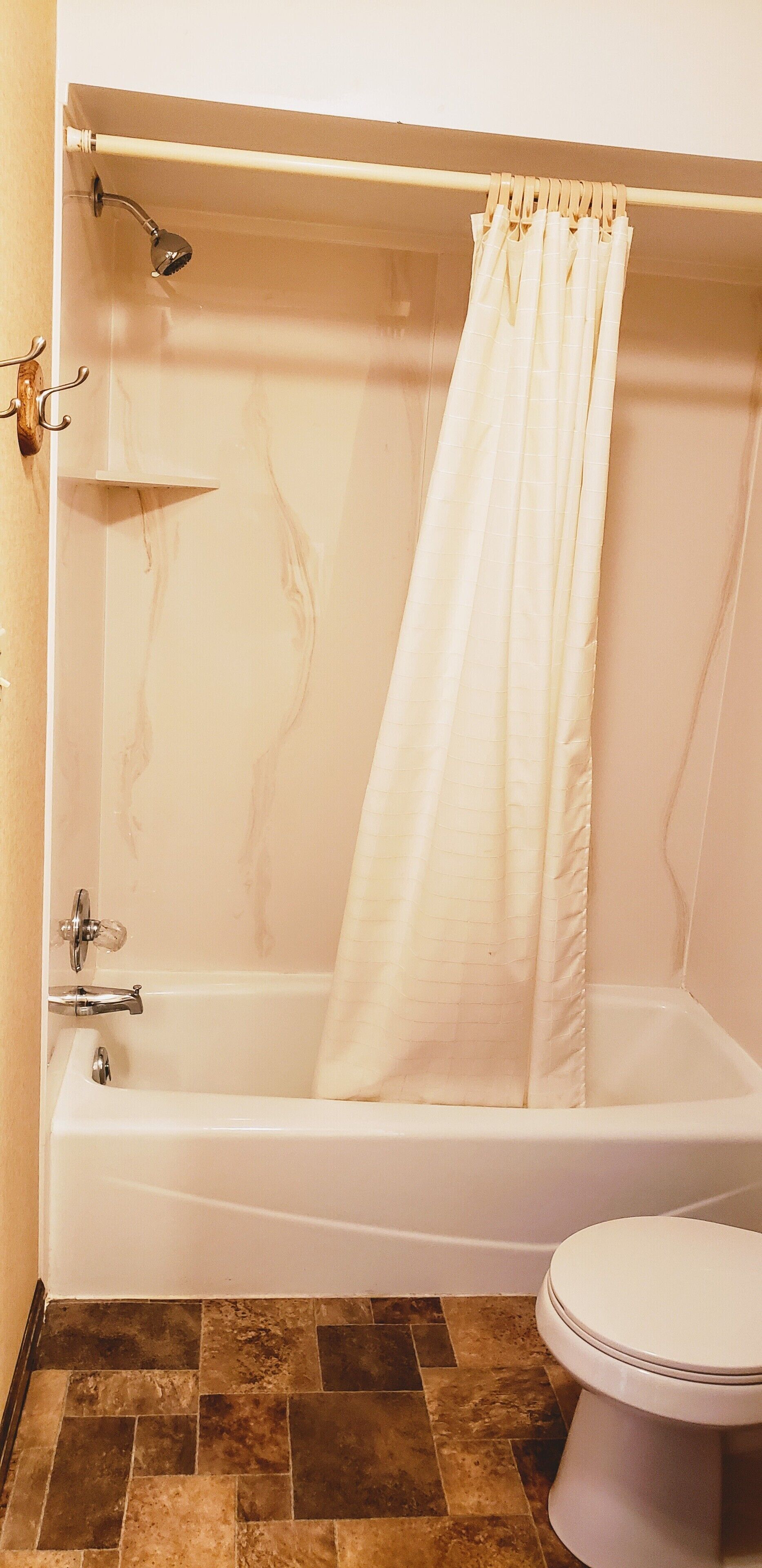 A bathroom with a bathtub, shower, and toilet.