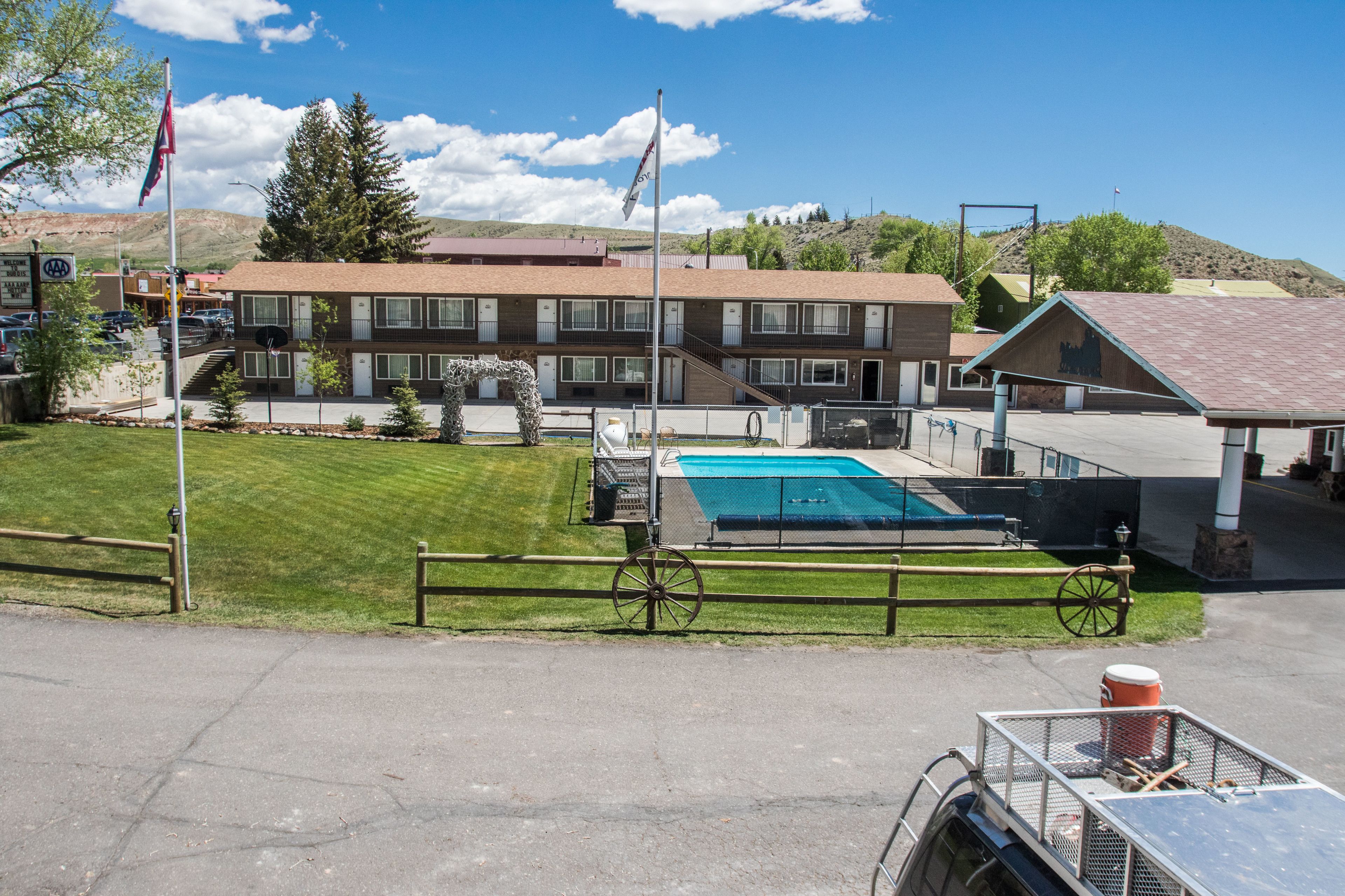 Ett hotell med en swimmingpool, ett inhägnat område och en bergskedja som bakgrund.