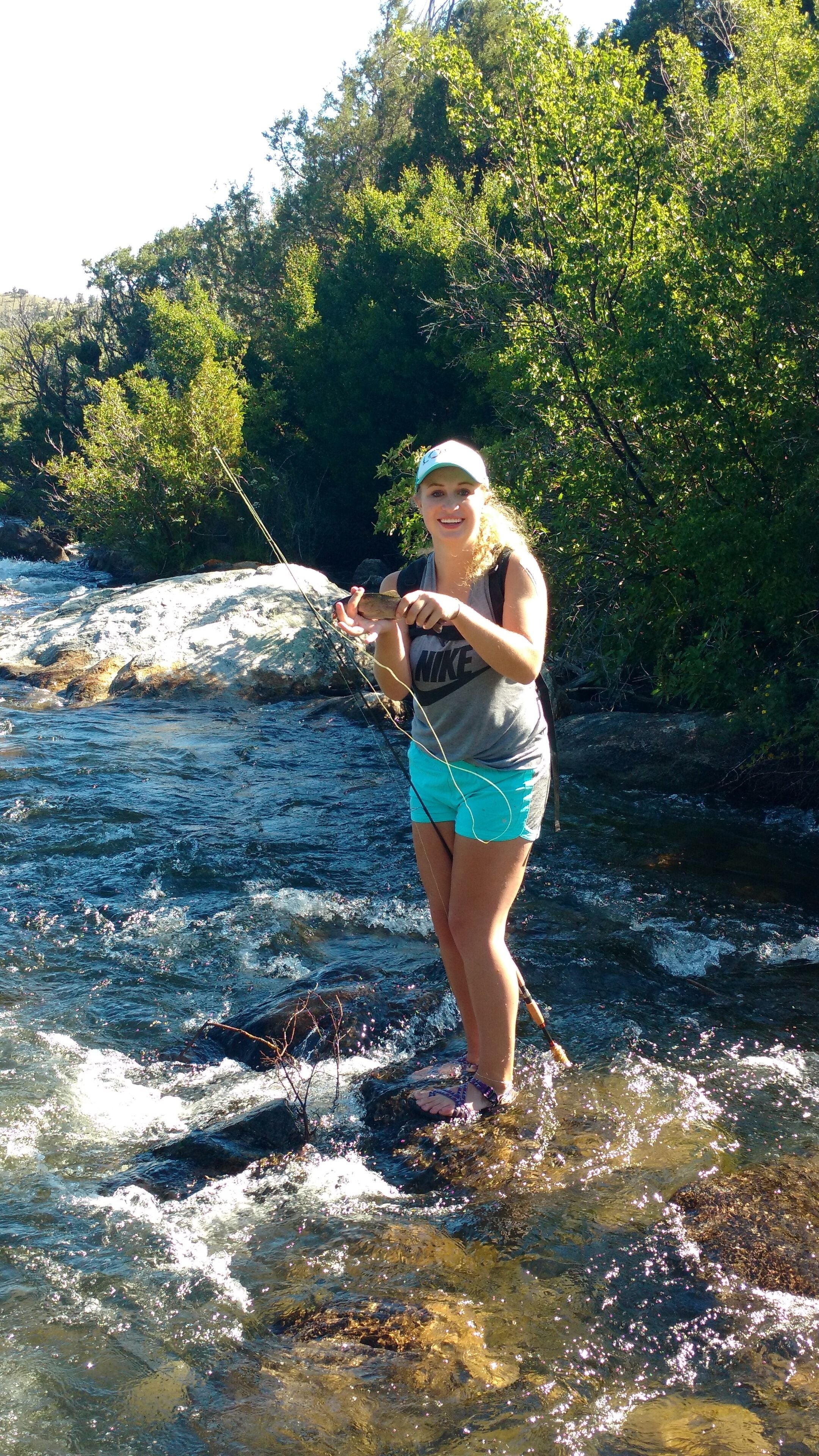 A person standing in a river, holding a fishing rod.
