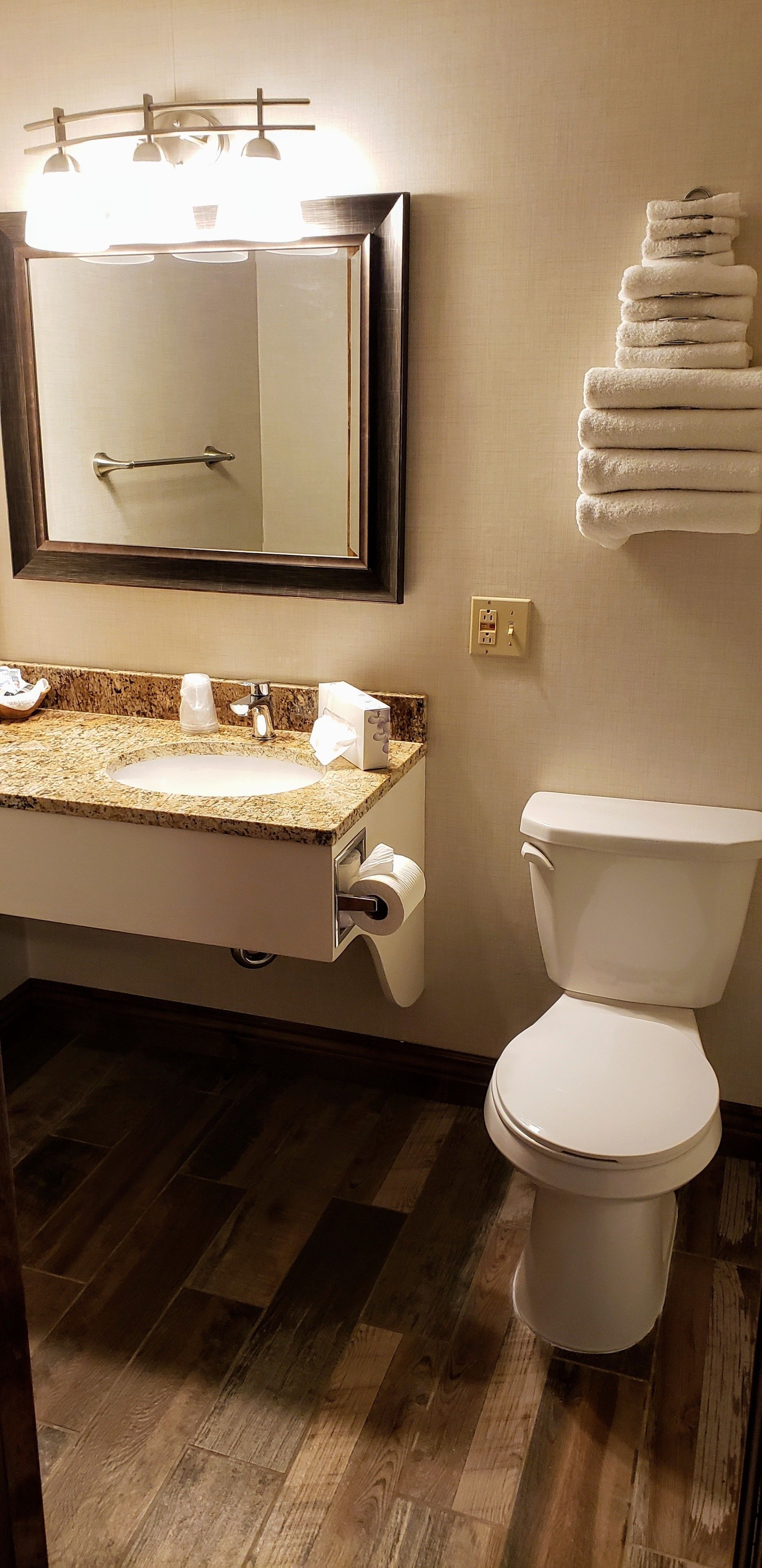 Un baño con lavamanos, espejo, toallero y retrete.