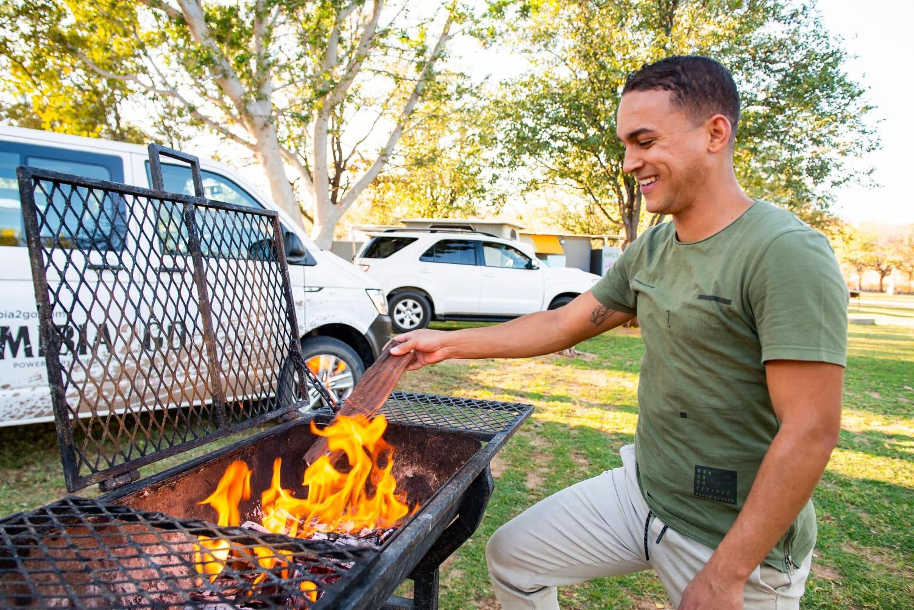 A person grilling outdoors with a vehicle in the background.
