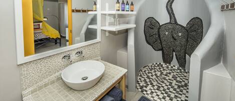 Un baño con lavamanos blanco, un espejo y suelo a cuadros.