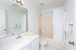 A bathroom with a sink, mirror, toilet, and shower.