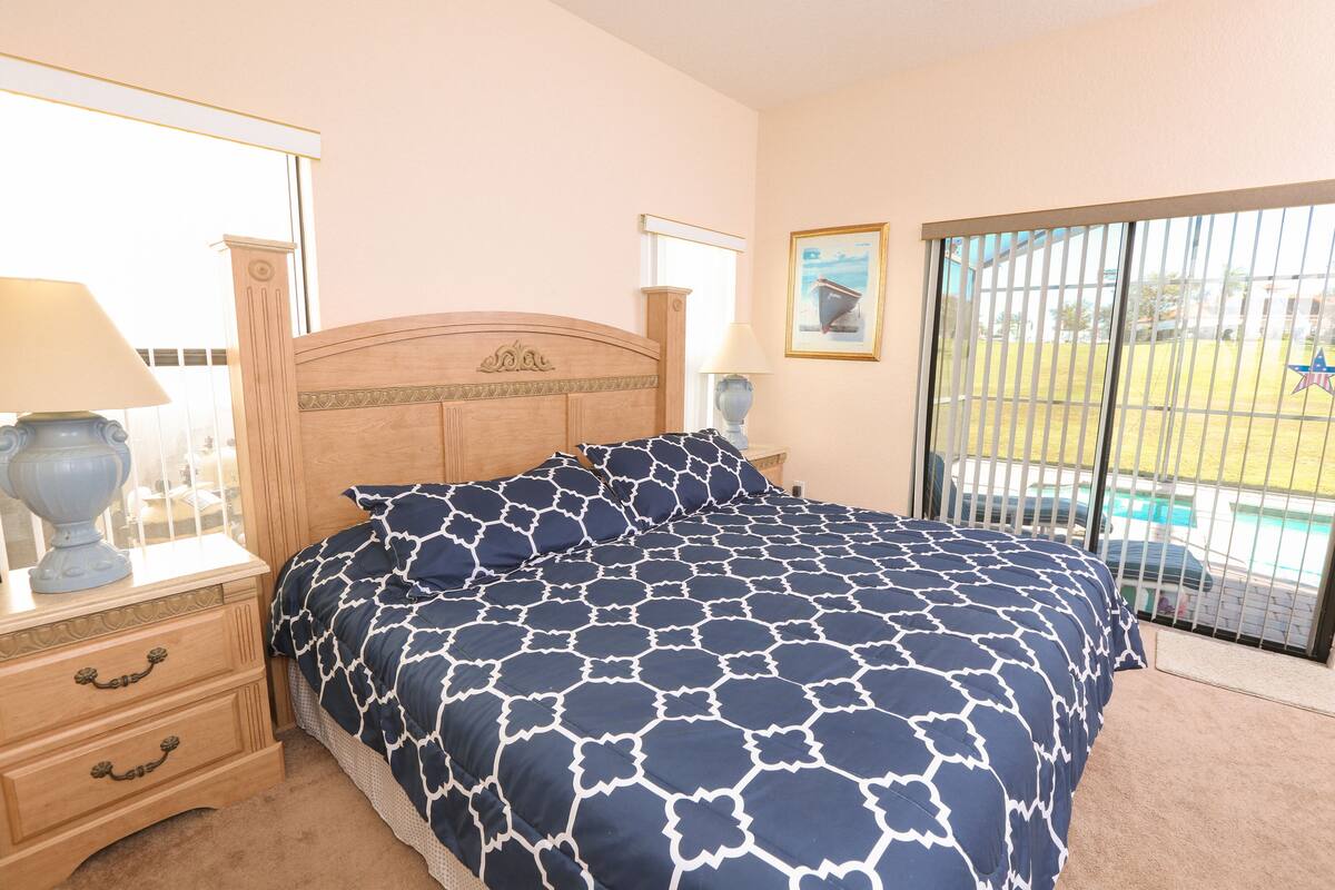 Een slaapkamer met een bed, twee nachtkastjes, een raam en uitzicht op een zwembad.