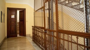 A hallway with a wooden door and a metal railing leading to a staircase. - Romerooms (Rome)