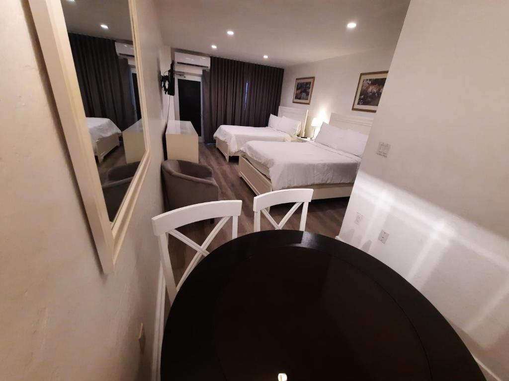 A hotel room with a bed, a desk, a chair, and a mirror.