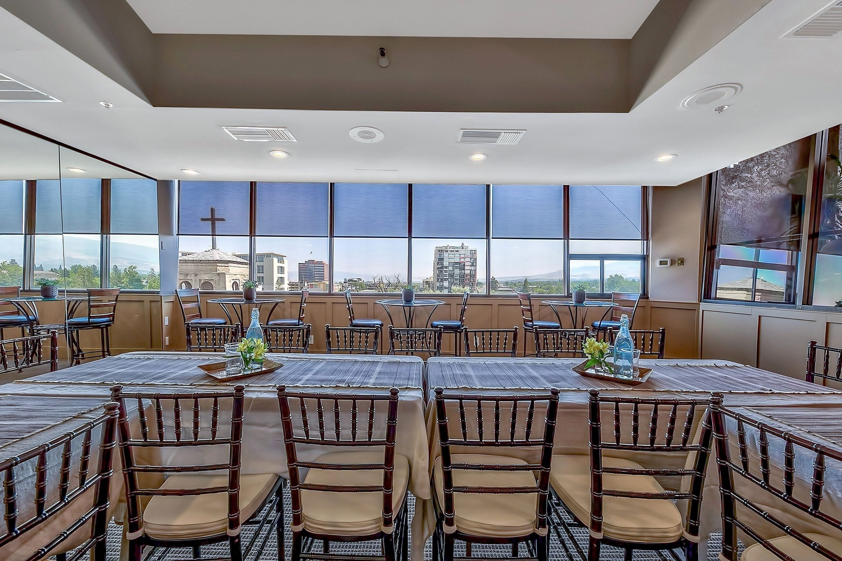 A spacious dining area with large windows, multiple tables, and chairs.