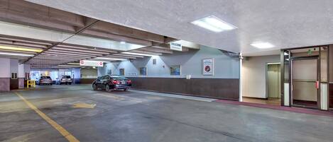 Eine Parkgarage mit geparkten Autos, einem Willkommensschild und einem Notausgang.