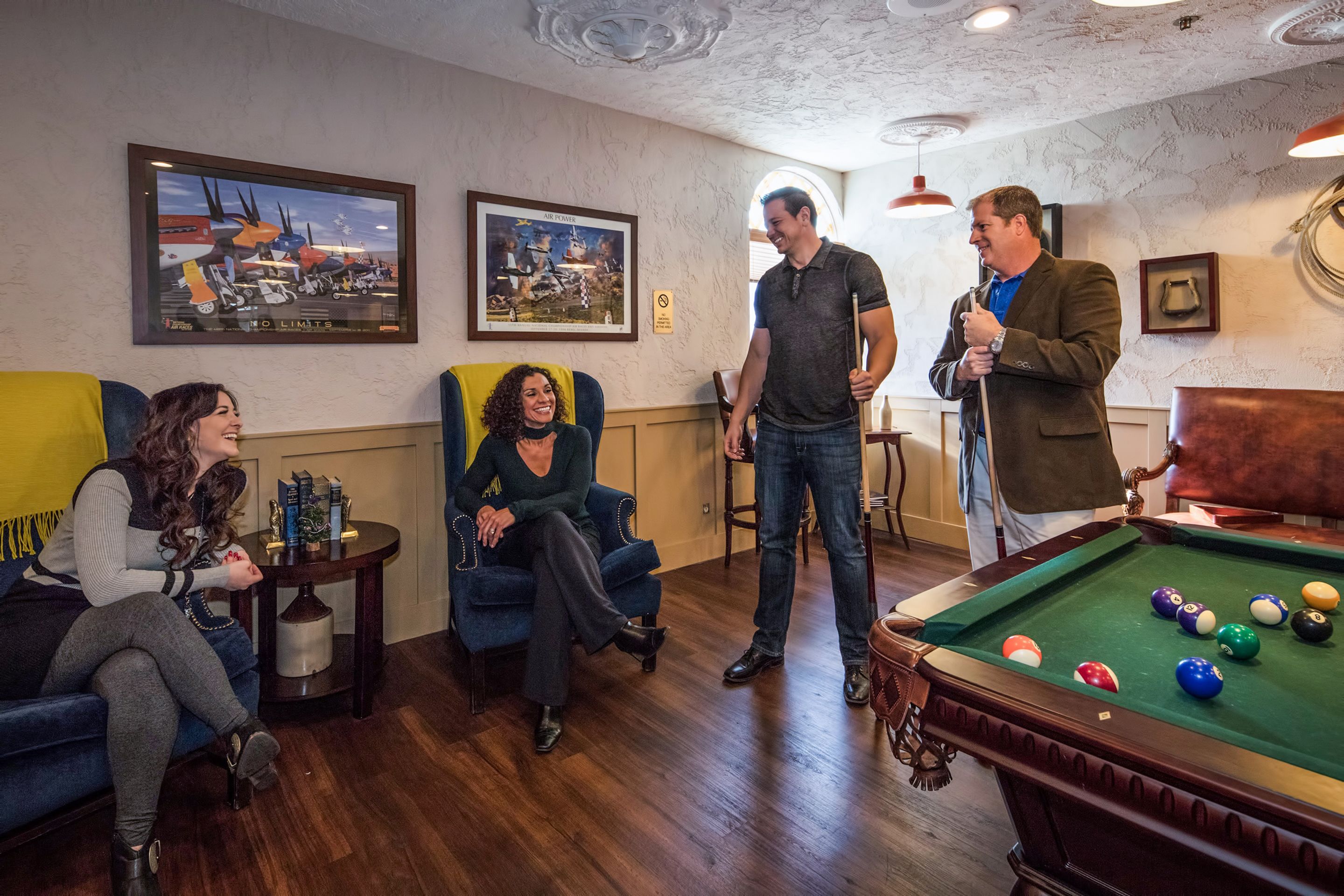 A billiards table with balls, a pool table, and two framed pictures on the wall.