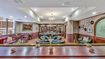 A spacious lobby with leather seating, a chandelier, and framed pictures on the walls.