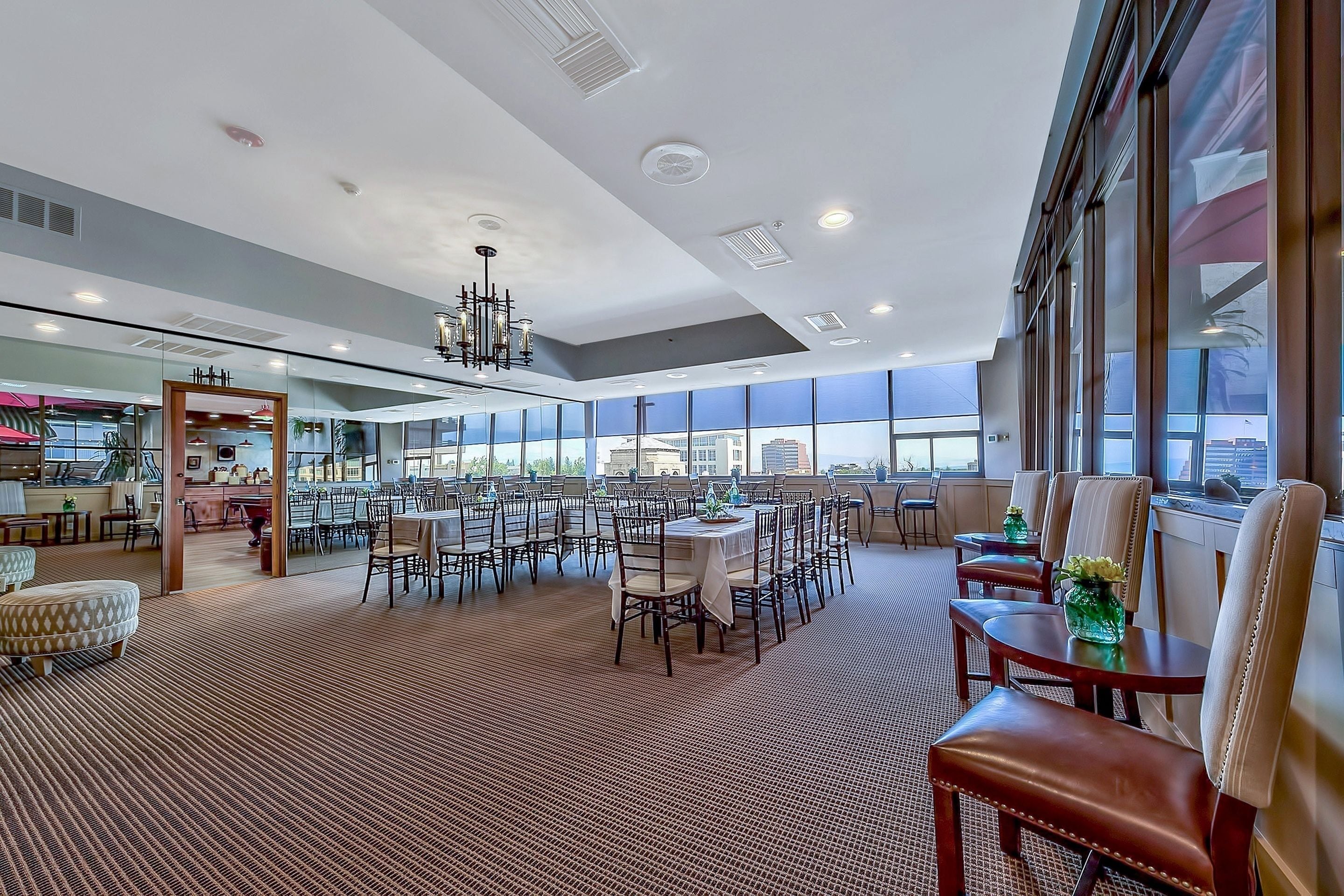 A spacious hotel lobby with a high ceiling, large windows, and a central chandelier.