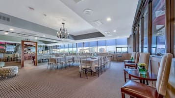 A spacious hotel lobby with a high ceiling, large windows, and a central chandelier.