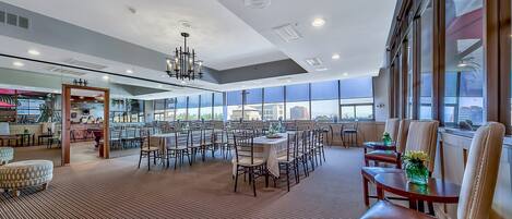 A spacious hotel lobby with a high ceiling, large windows, and a central chandelier.