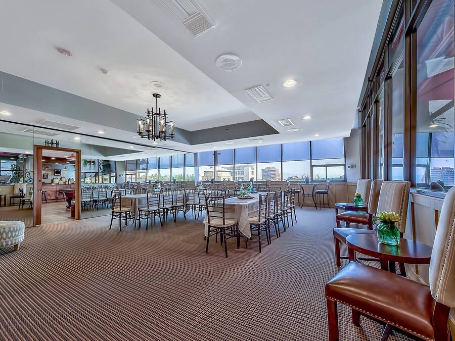 A spacious hotel lobby with a high ceiling, large windows, and a central chandelier.
