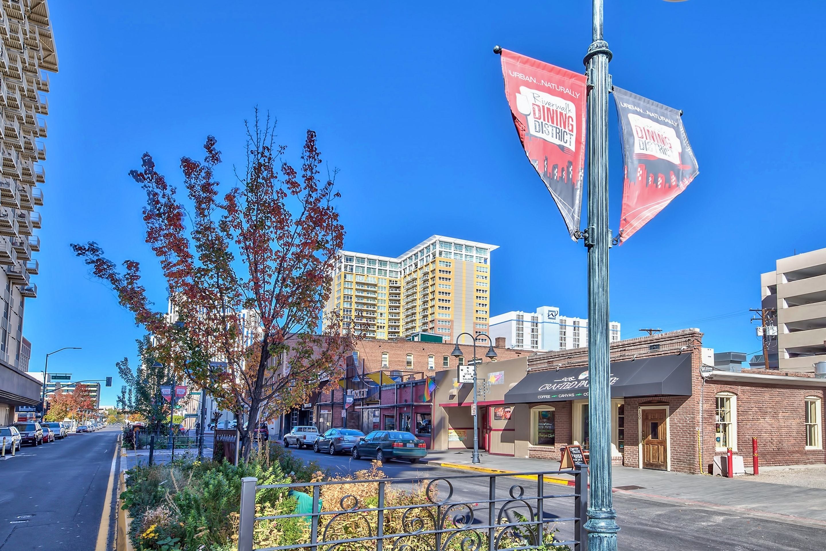 A street view with a flag advertising "Urban Dining District" and a building with a sign that reads "Canvas Coffee."
