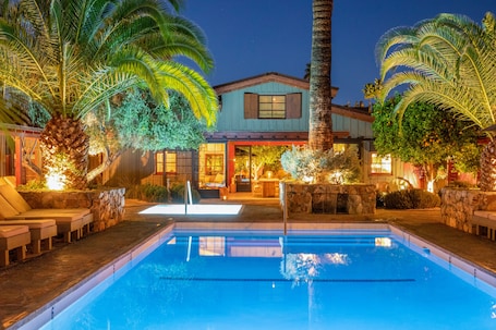 Una piscina al aire libre, sombrillas, sillones reclinables de piscina