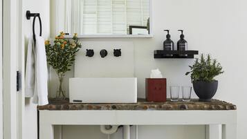 A bathroom with a white vanity, a mirror, and a shelf with toiletries.