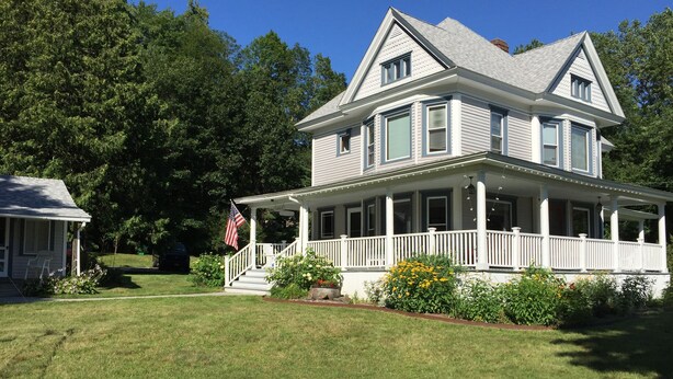 A two-story house with a porch, a small detached garage, and a well-maintained lawn. - The Blair House (Lake George)