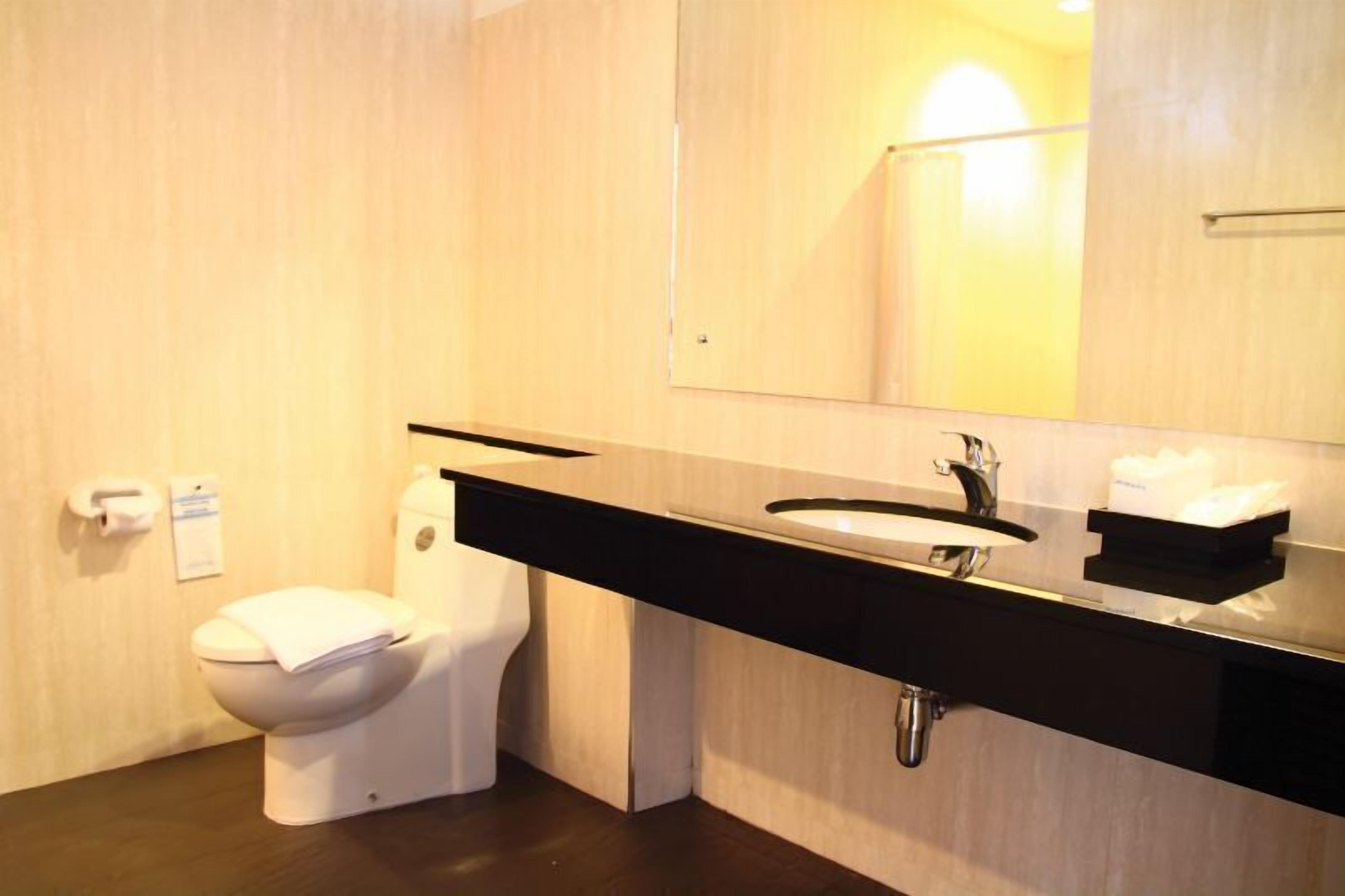 Un baño moderno con inodoro, lavamanos y espejo.