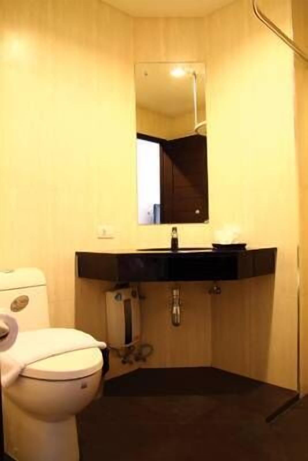 A bathroom with a toilet, sink, and mirror.