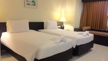 A hotel room with two beds, a nightstand, a lamp, a painting on the wall, and a window with curtains.