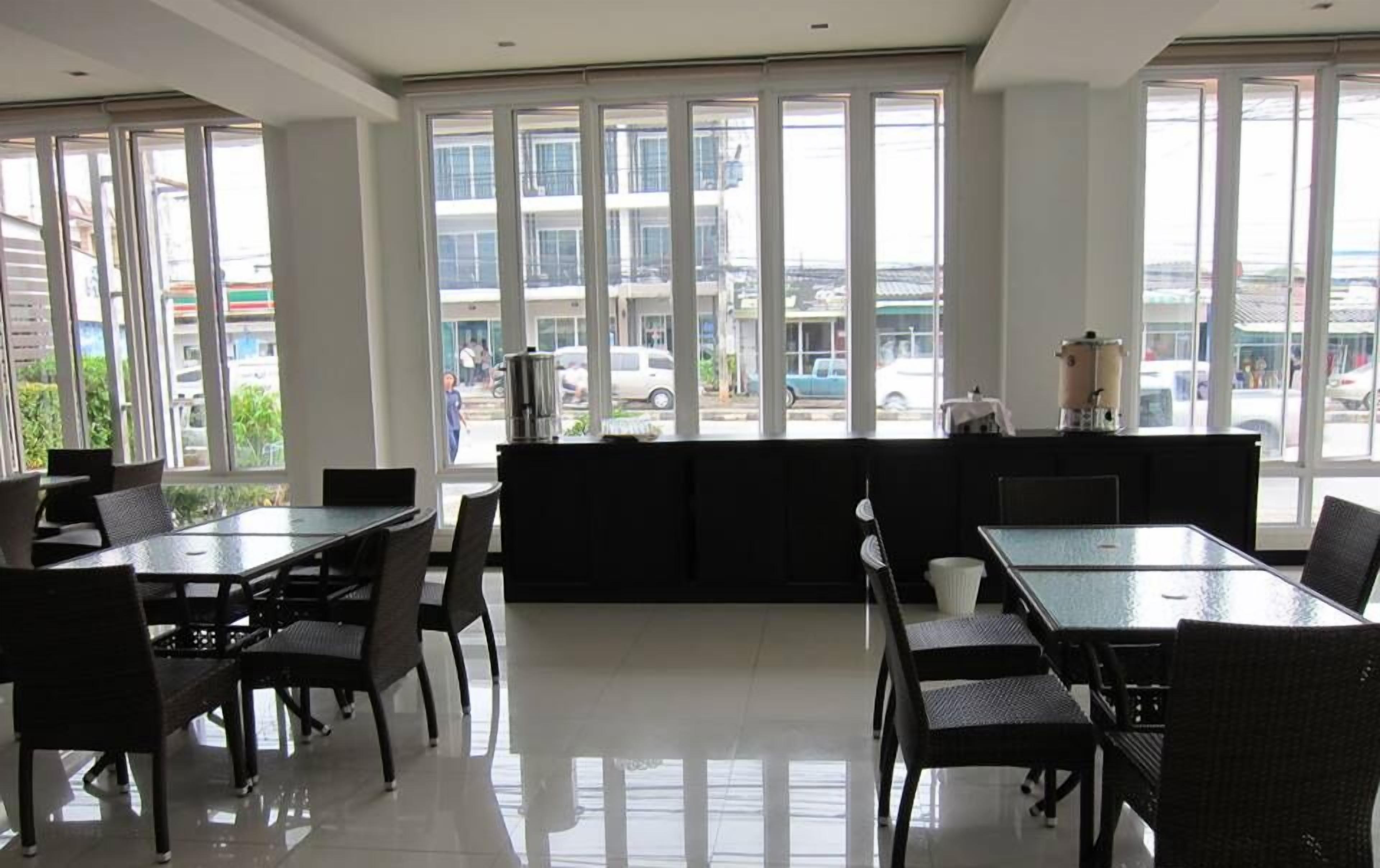 A modern restaurant with large windows, black furniture, and a view of the street.