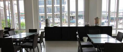 A modern restaurant with large windows, black furniture, and a view of the street.