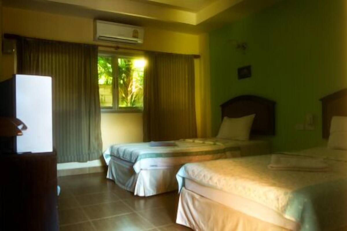 A hotel room with two beds, a television, and an air conditioning unit.