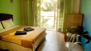 Ein Zimmer mit einem Bett, einem kleinen Tisch, einem Stuhl und Blick ins Freie durch ein Fenster.