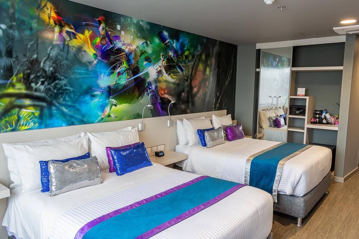 Una habitación de hotel con dos camas, un cuadro abstracto grande en la pared y un armario con estantes.