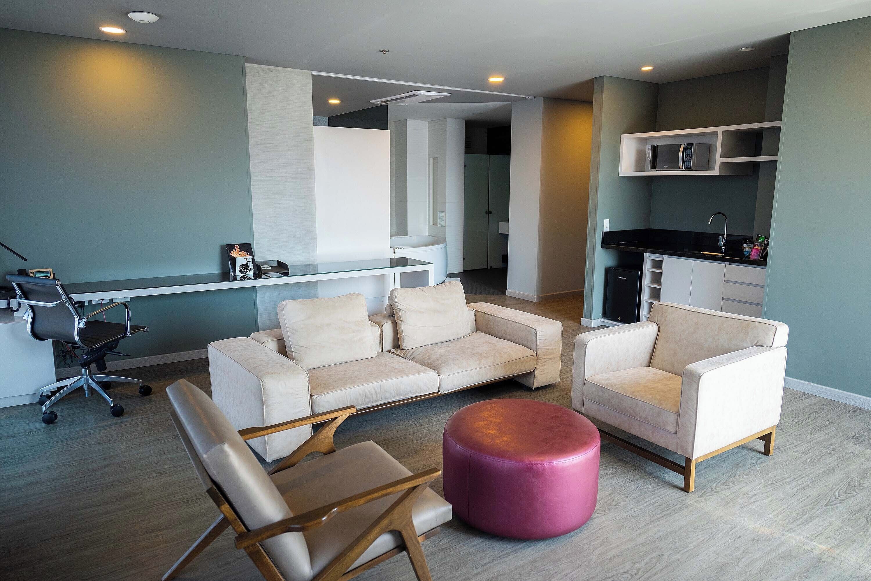 A modern living room with a sofa, ottoman, and a desk with a chair.