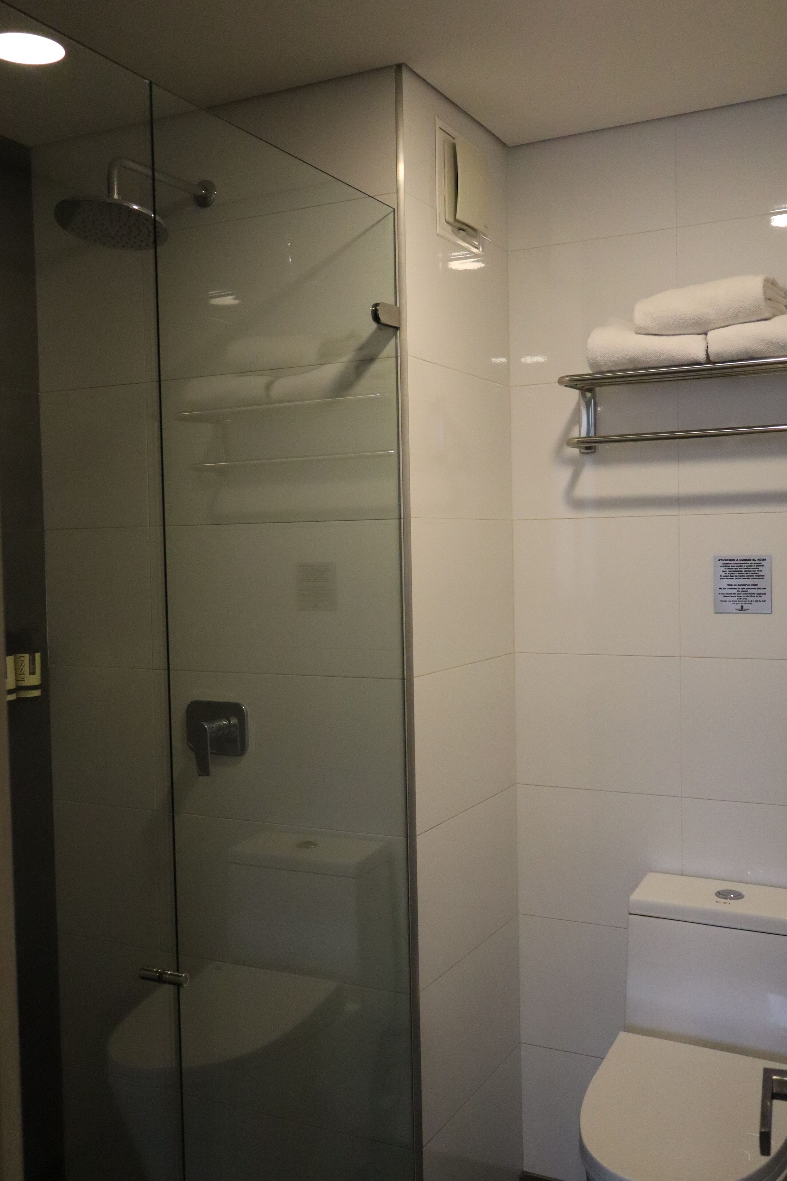 Ein modernes Badezimmer mit einer begehbaren Glasdusche, einer Toilette und einem Handtuchhalter.