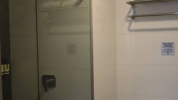 Ein modernes Badezimmer mit einer begehbaren Glasdusche, einer Toilette und einem Handtuchhalter.