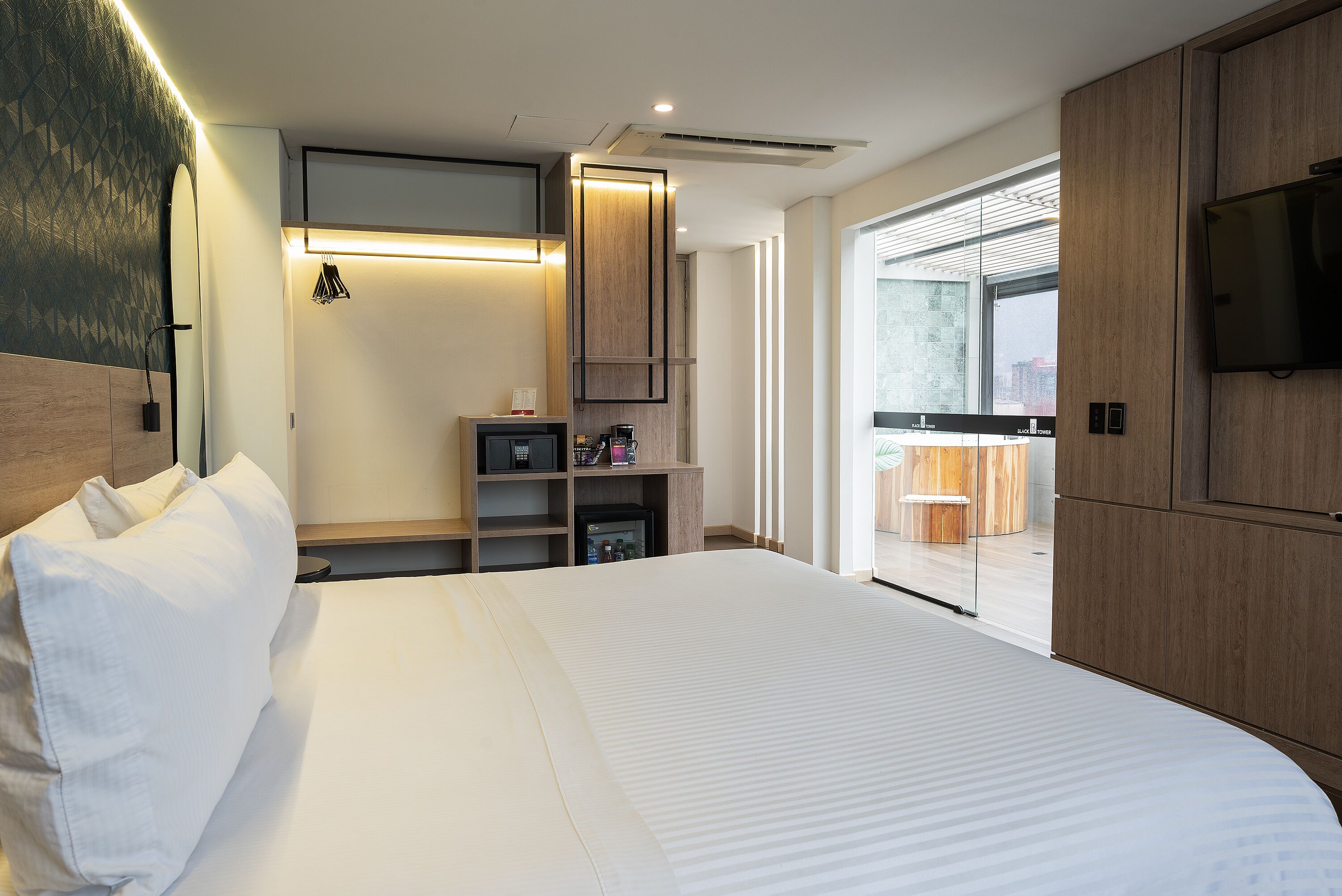 Habitación de hotel moderna con una cama grande, armario empotrado y vistas a la ciudad por la ventana.