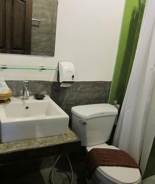 Un baño con lavamanos blanco, inodoro y secamanos.
