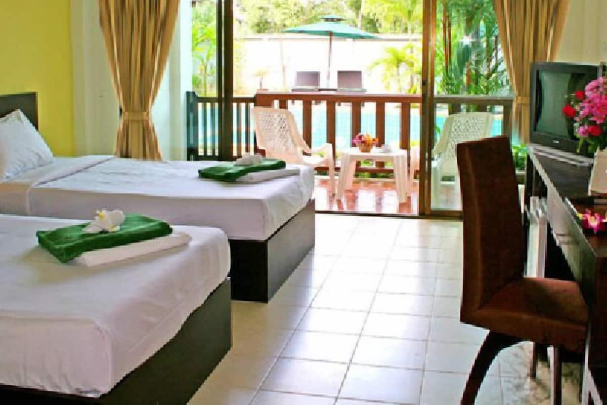 Une chambre d’hôtel avec deux lits, un bureau avec un ordinateur, une télévision et un balcon équipé d’une table et de chaises.