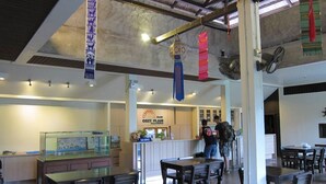 Un restaurante con mostrador, mesas y un acuario.