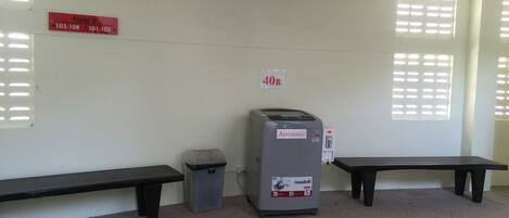 Ein Raum mit zwei Bänken, einem Mülleimer und einem Automaten.
