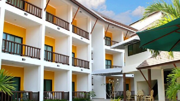 Un hotel de varios pisos con balcones, piscina y mobiliario exterior.