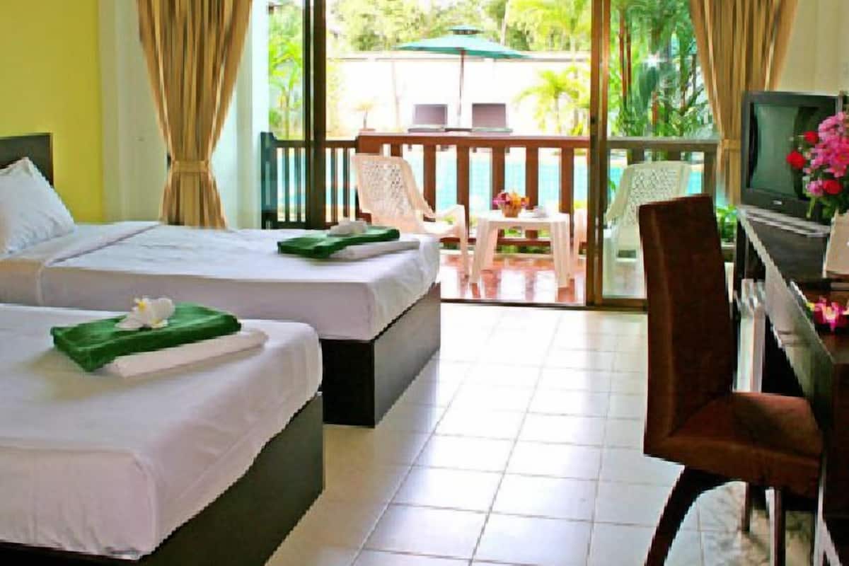 Une chambre d’hôtel avec deux lits, un bureau avec un ordinateur, une chaise et un téléviseur. Il y a un balcon avec une table et des chaises.