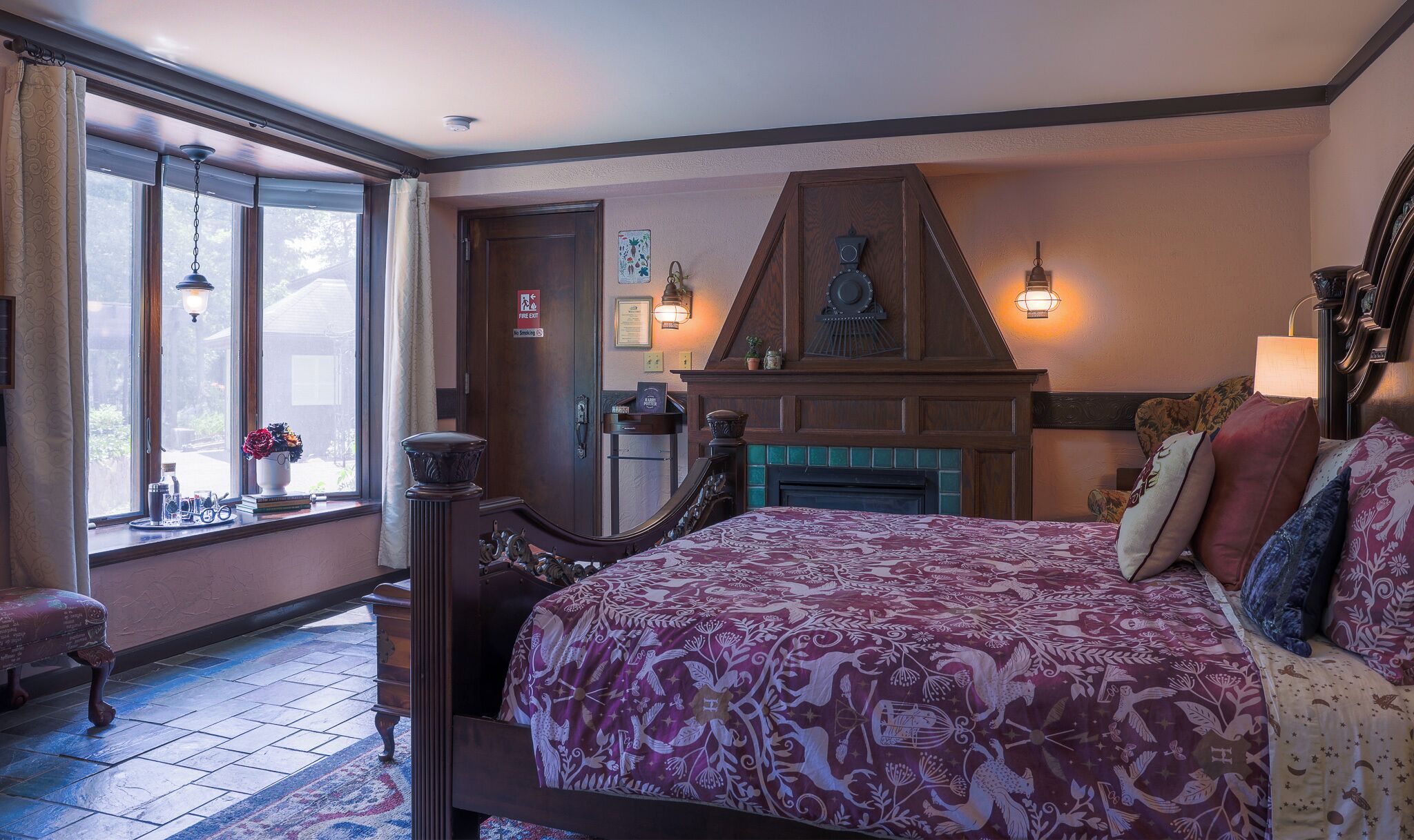 A bedroom with a large bed, a fireplace, and a window with curtains.