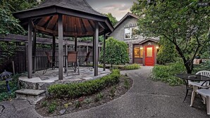 A gazebo with chairs, a stone pathway, and a house with a red door. - Stone Chalet B&B Inn and Event Center (Ann Arbor)
