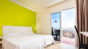 A hotel room with a large bed, a bright green wall, a balcony with a view, and a chair. - Kn Aparthotel Panoramica Heights (Adeje)