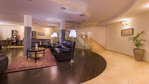 A modern living room with a curved ceiling, dark wood flooring, leather sofas, a glass coffee table, and a red patterned rug. - Kn Aparthotel Panoramica Heights (Adeje)