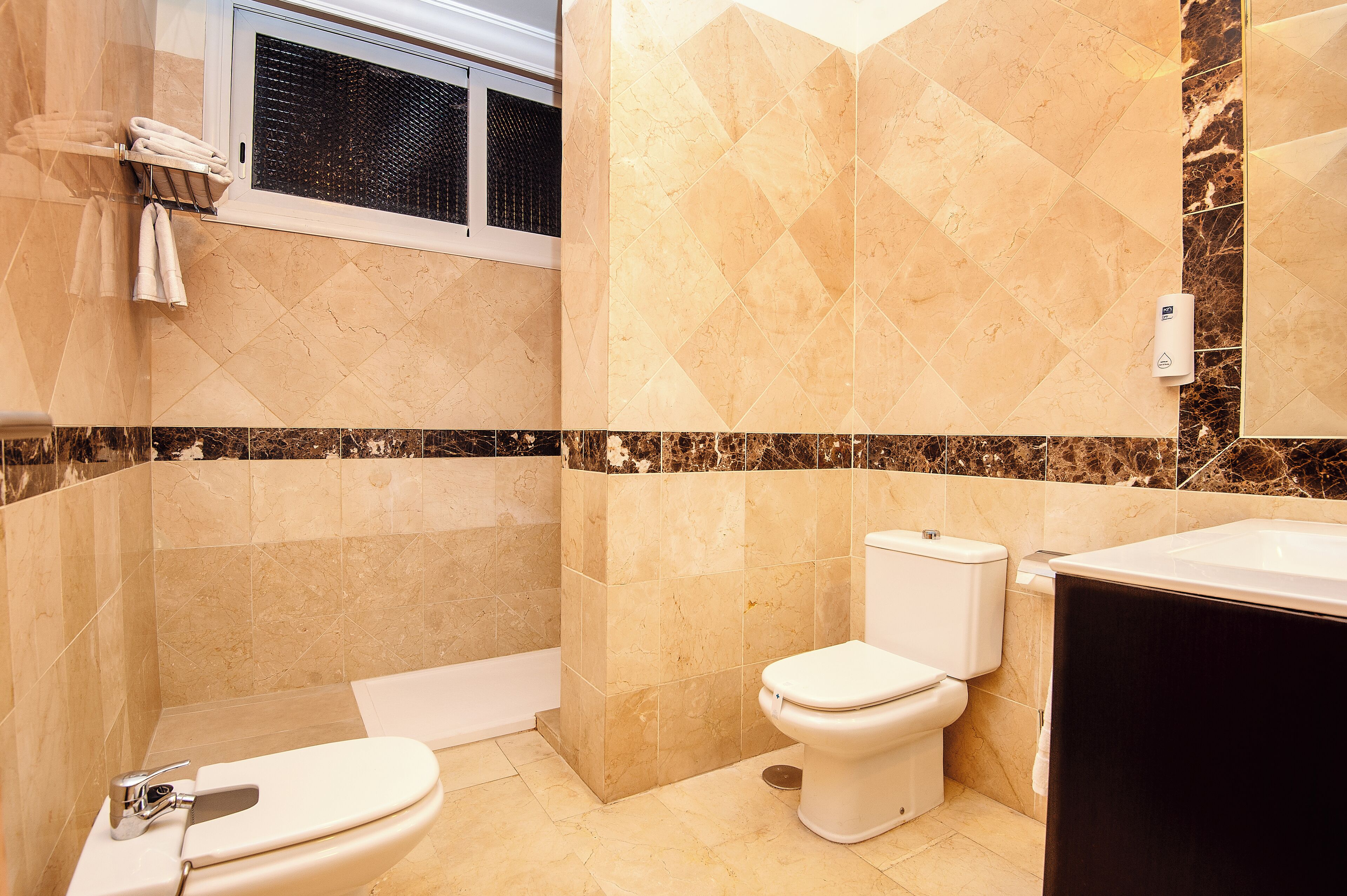A bathroom with a toilet, bathtub, and a towel rack with towels.