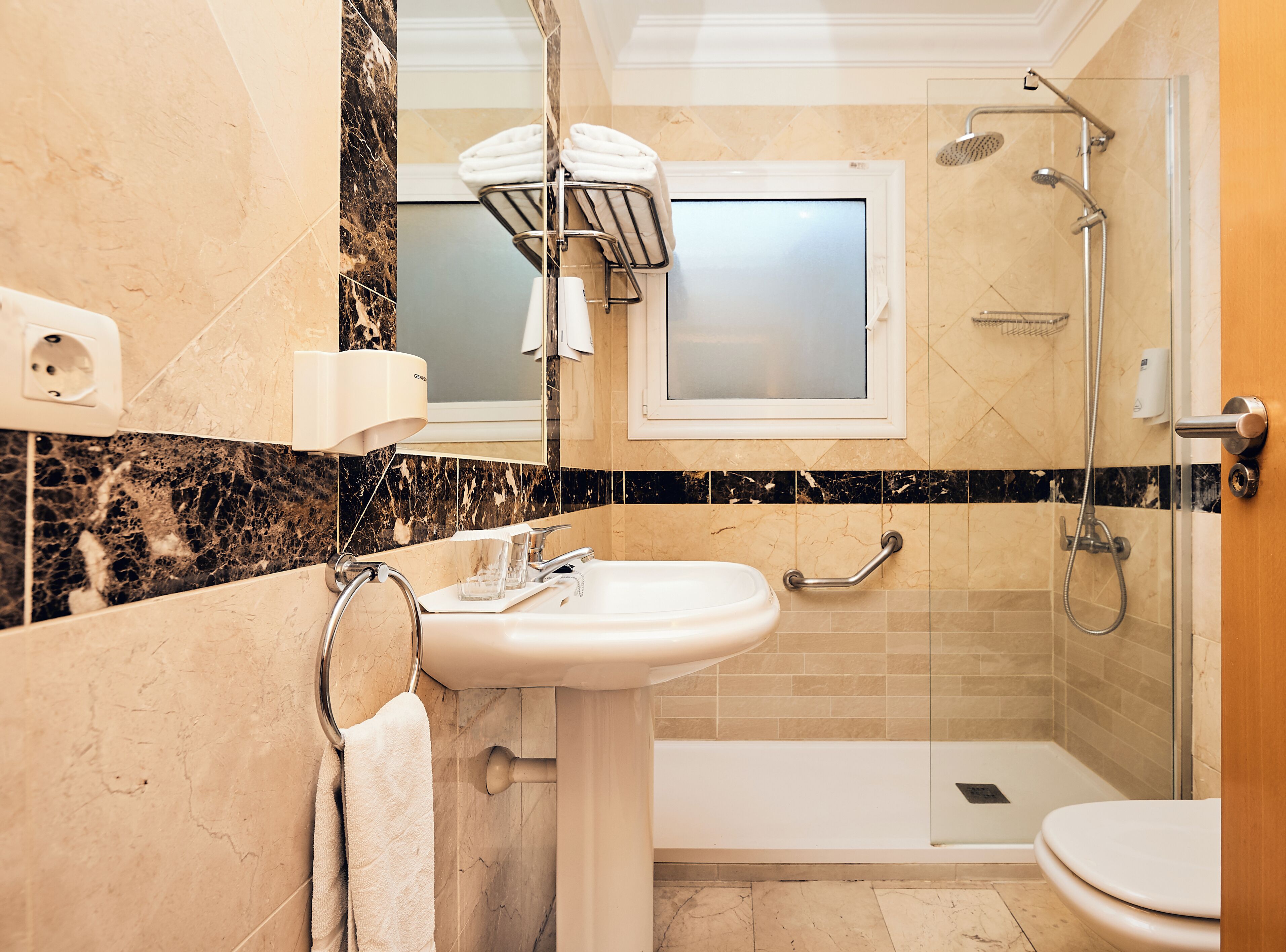 A modern bathroom with a sink, mirror, towel rack, shower, and toilet.
