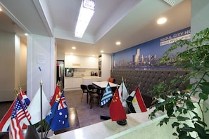 Un espace repas décoré de drapeaux, orné d’une fresque représentant un paysage urbain, et avec une cuisine moderne en arrière-plan.