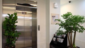 Ein Aufzug mit digitaler Anzeige, einem Blumentopf und einer Pinnwand mit einer Karte sowie einem Hinweis für die Seoul City Tour.
