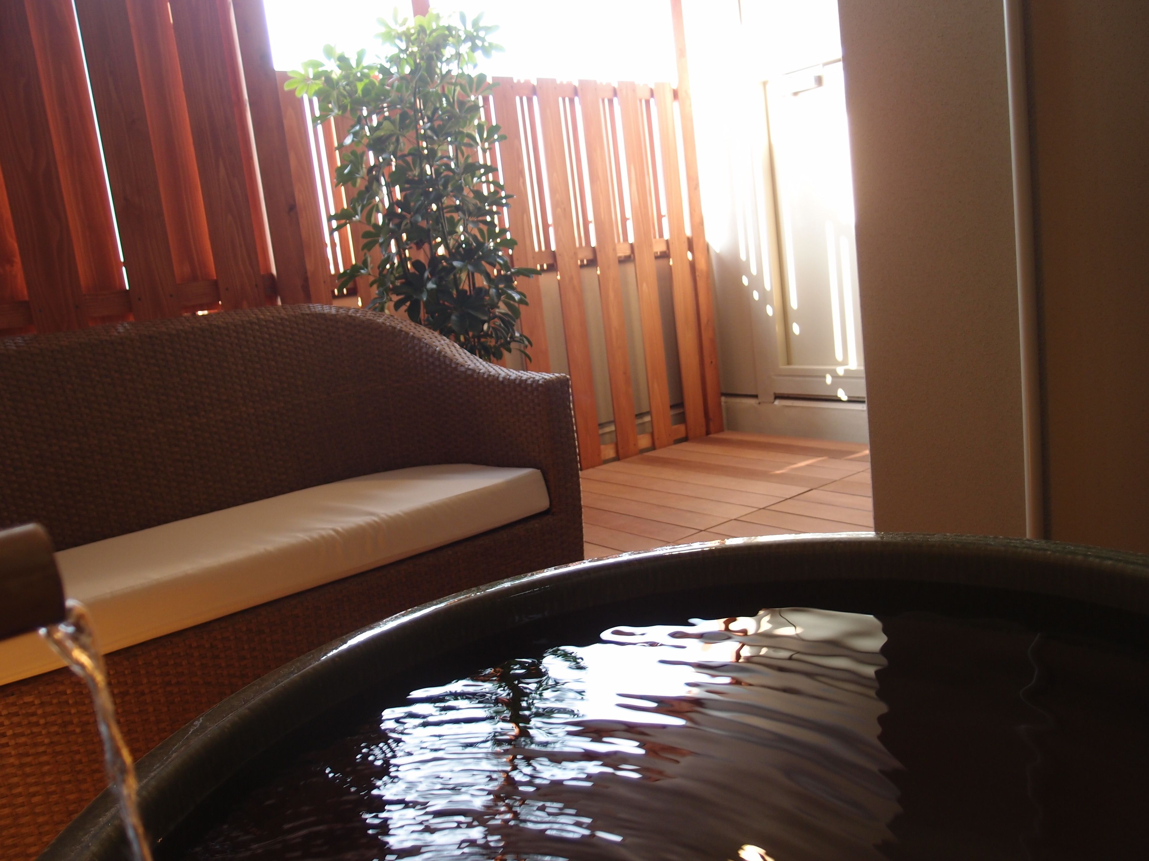 A room with a wooden bench, a large black bathtub, and a wooden fence in the background.