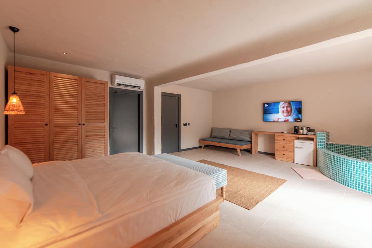 Un dormitorio con cama, escritorio, televisor y baño.